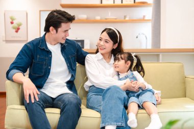 Aile bir zeytin kanepesinde gülümser; ebeveynler kızlarıyla kapalı bir aile sahnesinde samimi bir anı paylaşır