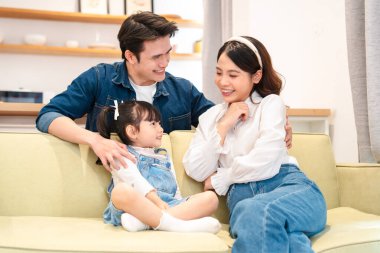 Üç kişilik bir aile evde eğleniyor ebeveynler sevimli kızlarını izliyor ve hayranlık duyuyorlar.