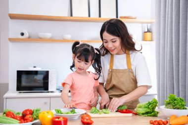 Anne ve kız, mutfakta sağlıklı yemekler hazırlarken birbirlerine bağlanıyorlar. Sağlıklı beslenme ve aile.