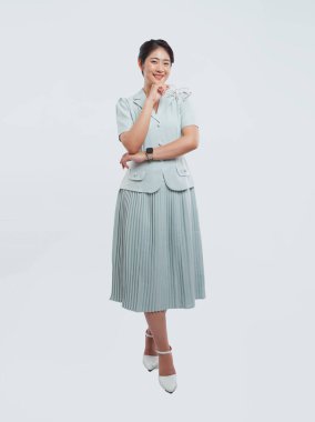 Açık mavi bir elbise giyen gülümseyen bir kadın düz bir arkaplanda gözlük tutuyor.