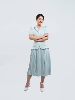 Açık mavi takım elbiseli, beyaz topuklu beyaz etekli, beyaz elbiseli, gülümseyen bir kadın.