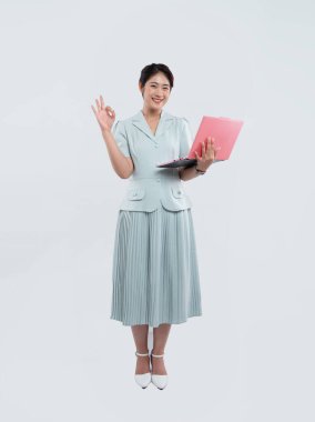 Şık, açık yeşil takım elbiseli neşeli bir insan elinde bir dizüstü bilgisayar tutuyor ve temiz bir arkaplan için onay işareti veriyor.