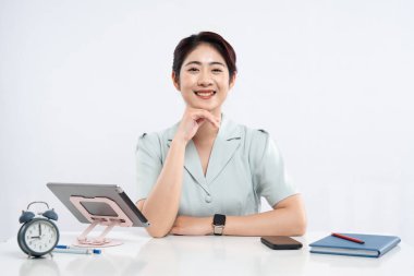 Masadaki profesyonel kadın elektronik tablet defter ve diğer ofis aksesuarlarıyla poz veriyor.