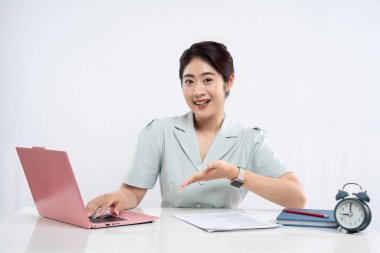 Gülümseyen bir kadın bilgisayarı üzerinde çalışıyor. Ekrana doğru temiz bir şekilde sunuyor.