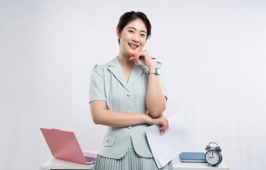 Ofisteki genç profesyonel bir kadın elinde belgeleri ve kalemini görevleri için hazırlıyor.