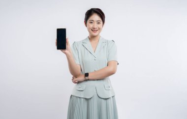 Kendine güvenen bir kadın, elinde boş bir ekranla bir akıllı telefonu tutarken gülümsüyor.