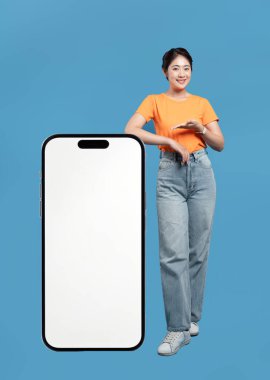 Gülümseyen bir kadın, büyük ekran boş bir akıllı telefonu mavi bir arka planda sergiliyor.