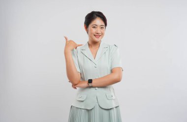 Bir kadın stüdyo ortamında açık renkli etek ve bluz giyerek 