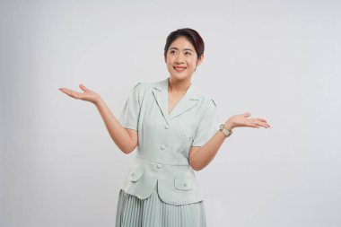 Kadın, şık, soluk yeşil bir takım elbise ve pileli bir etek ve kol saati ile görsel bir alan sunar.