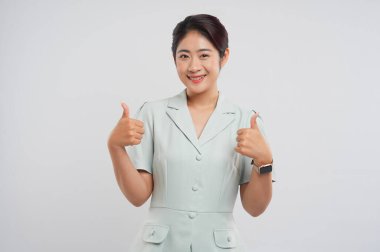 Yeşil bluz giyen gülümseyen kadın arka planda baş ve omuz hareketi yapıyor.