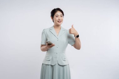 Neşeli bir yüzü olan genç bir kadın akıllı telefonunu tutar ve onaylı bir jest yapar.