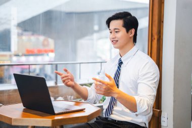 Kafede neşeli bir profesyonel dizüstü bilgisayarında toplantı yapıyor. Kravat takıyor.