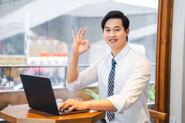 Bir kafede bilgisayarında çalışan Asyalı profesyonel kameraya 