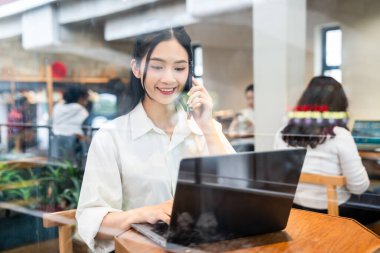 İş için dizüstü bilgisayar ve telefon kullanan bir kadın. Uzak iş yeri ve modern teknoloji.