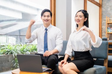 İki gülümseyen ofis arkadaşı bir erkek ve bir kadın işyerindeki başarılarından dolayı heyecanlarını gösteriyorlar.