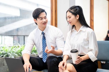 Akıllı giyimli iki genç profesyonel bir ofis ortamında buluşup bir projeyi tartışıyorlar.