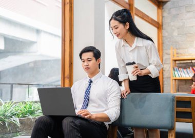 İyi aydınlatılmış bir çalışma alanında, pencerenin yanında kahve eşliğinde bir dizüstü bilgisayarda iş birliği yapan iki meslektaşım.