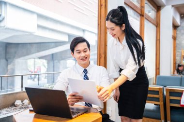 İki meslektaşı bir projede işbirliği yapıyor. Biri, belgelerin incelenmesinde diğerine yardım ediyor.