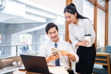 İş kıyafetleri giymiş iki meslektaş, bir kafede ya da işyerinde birlikte akıllı telefonu inceliyor.