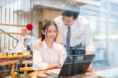 Bir kadın ve erkek iş birliği yapıp dizüstü bilgisayara bakıyorlar. Atmosfer odaklanmış ve pozitif.