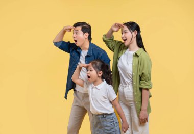 Baba, anne ve kız, sarı zemine karşı hayret verici ifadelerle uzaklığa bakıyorlar.