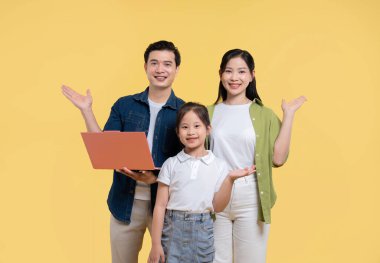 Üç kişilik bir aile sarı bir arka plana karşı birlikte duruyor ve seyircilere neşeyle bir şeyler sunuyor.