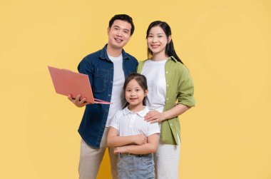 Üç kişilik mutlu bir aile anne ve kız dizüstü bilgisayarla poz veriyorlar.