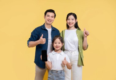 Üç çocuklu Asyalı aile stüdyoda poz veriyor ve sarı arka plan veriyor.