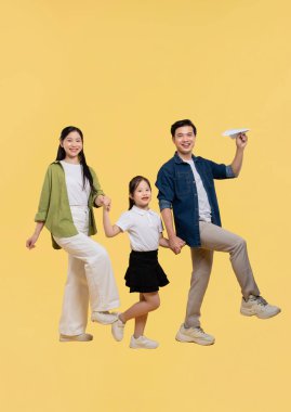 Mutlu bir aile, anne baba ve kızı da dahil. Sarı bir arkaplanda birlikte yürüyorlar.