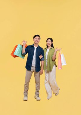 Mutlu bir çift alışveriş yaptıktan sonra gülümsüyor ve alışveriş torbalarını tutuyor.