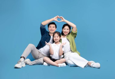 Açık mavi üzerinde neşeli bir aile portresi: Ebeveynler kızlarının üzerinde bir kalp oluşturuyorlar hepsi parlak bir şekilde gülümsüyor