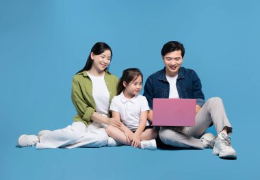 Üç kişilik bir aile bir anne baba ve kızı birlikte dizüstü bilgisayara bakıyor.