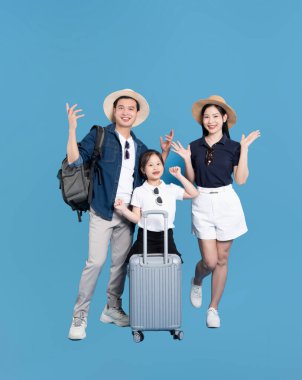 Bir çocuk da dahil olmak üzere bir aile bavullarıyla canlı mavi bir arka plana atlamak için hazır bekliyor.