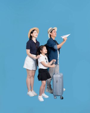 Bir aile, mavi arka planda bir bavulla bir kağıt uçak tutarak seyahat etmeyi dört gözle bekliyor.