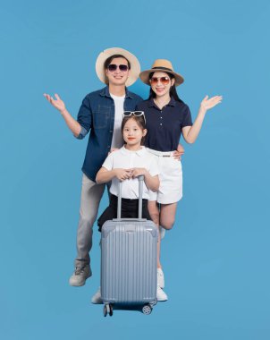 Üç kişilik neşeli bir aile tatil için giyinmiş, şapka ve güneş gözlüğü takmış, bavullarıyla poz veriyorlar.