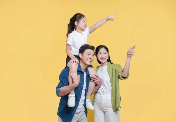 Neşeli bir aile, babasının omuzlarına binen küçük bir kız da dahil olmak üzere geleceğe bakıyor.