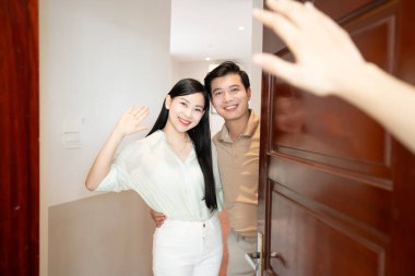 Memlekette neşeli bir çift, ziyaretçileri gülümseme ve el sallayarak karşılıyor.