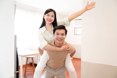 Mutlu bir çift, neşeli bir anı paylaşır. Parlak, modern bir evde. Onu sırtında taşır.