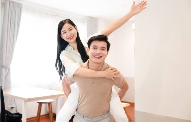 Gülümseyen bir kadın neşe dolu parlak bir odada sırtına biner.