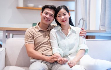 Mutlu çift evlerindeki kanepede kucaklaşırken gülümsüyor ve sıcak ve davetkar bir ortam yaratıyor.