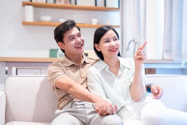 Neşeli bir çift koltukta oturup el ele tutuşur ve heyecan ve heyecanla pencereye bakar.