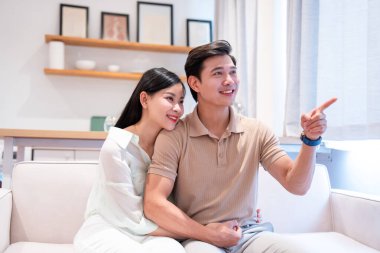 Parlak bir odada gülümseyen bir çift partnerini koltuğa yaslar.