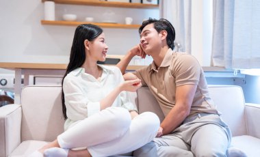 Bir çift, aydınlık bir alanda koltukta oturup samimi bir sohbete daldıklarında gülümserler.