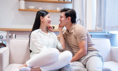 Sevgi dolu bir çift, beyaz bir kanepede, rahat ve mutlu bir şekilde birbirlerine bakıyorlar.