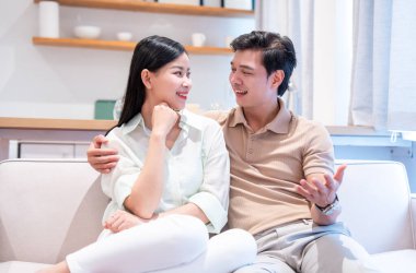 Sevgi dolu bir çift, oturma odasındaki bir koltukta rahatça oturur ve gülücüklerle sohbet eder.