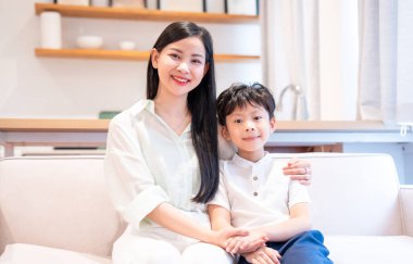 Bir anne ve oğul evlerinde rahat bir koltukta otururken bir portre için poz verirler.