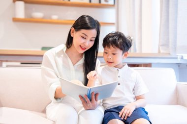 Bir anne ve oğul, parlak bir kanepede oturup, eğitici bir anı anlatan bir kitap okuyorlar.