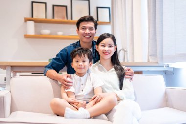 Üç kişilik bir aile. Bir erkek, bir kadın ve bir çocuk. Bir kanepede gülümsüyorlar.