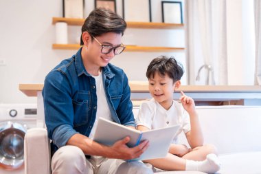 Bir ebeveyn, rahat bir evde çocuğuyla kitap paylaşır ve kitap okuyarak bir bağ kurar.