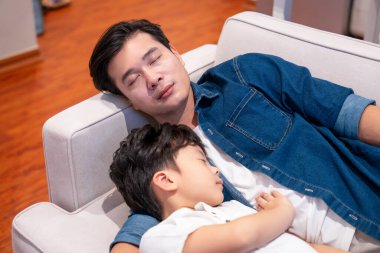 Baba ve oğul rahat ve rahat bir oturma odasında kanepede kestiriyorlar.